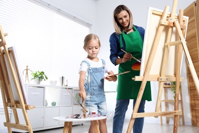 Photo of Choice of profession. Mother teaching her daughter to paint in studio, low angle view