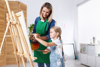 Photo of Choice of profession. Mother teaching her daughter to paint in studio
