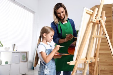 Photo of Choice of profession. Mother teaching her daughter to paint in studio