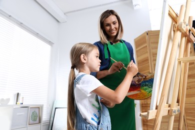 Photo of Choice of profession. Mother teaching her daughter to paint in studio, low angle view