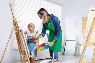 Photo of Choice of profession. Mother teaching her daughter to paint in studio