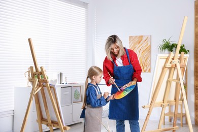 Photo of Choice of profession. Mother teaching her daughter to paint in studio