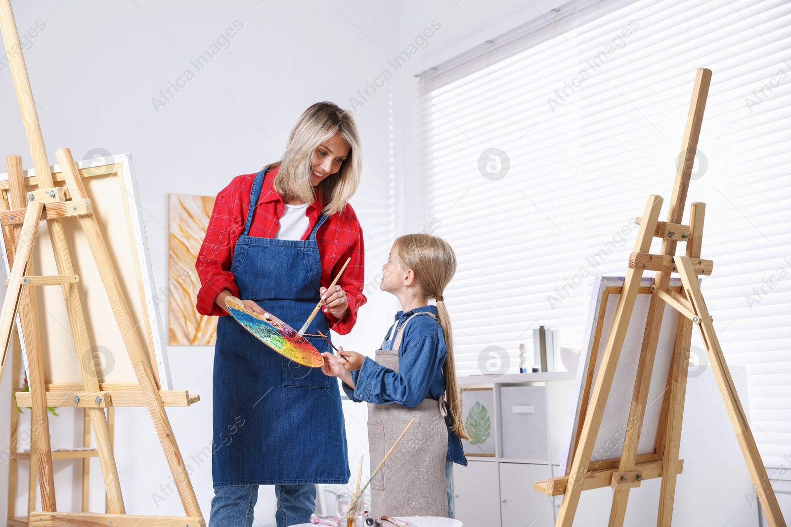 Photo of Choice of profession. Mother teaching her daughter to paint in studio