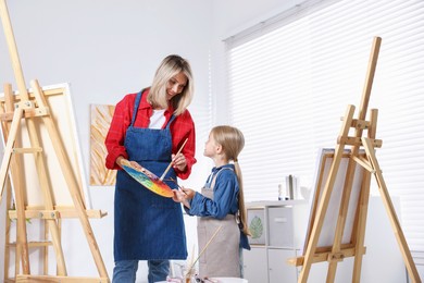 Photo of Choice of profession. Mother teaching her daughter to paint in studio