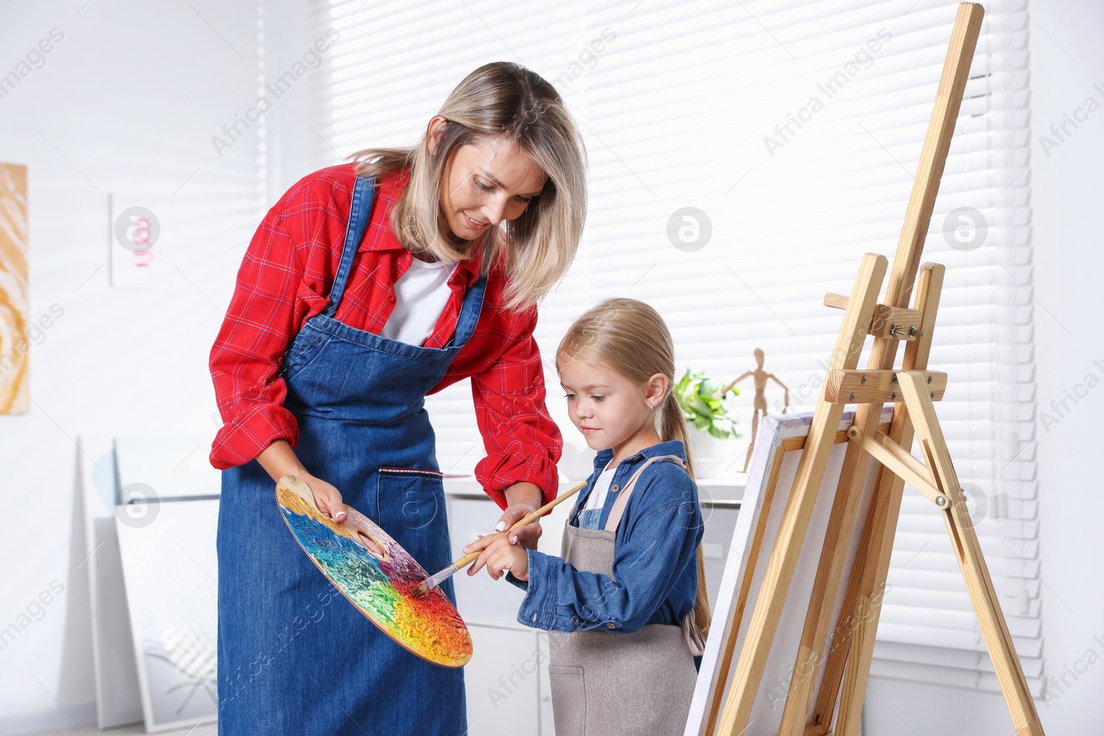 Photo of Choice of profession. Mother teaching her daughter to paint in studio