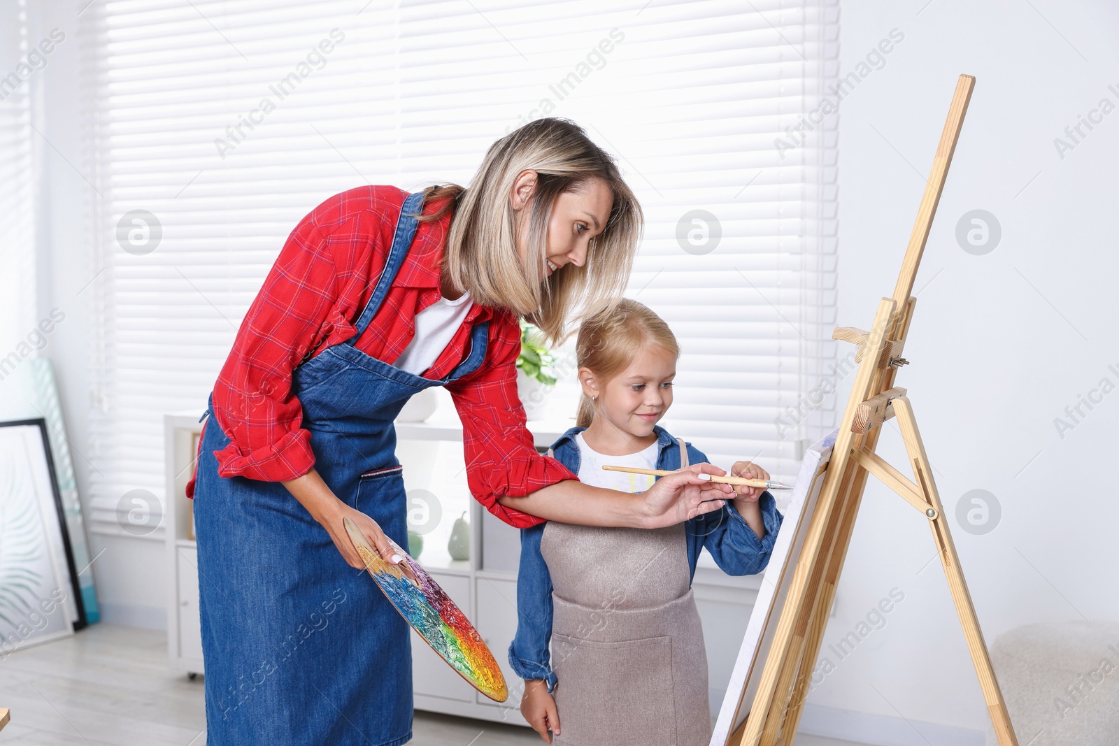 Photo of Choice of profession. Mother teaching her daughter to paint in studio