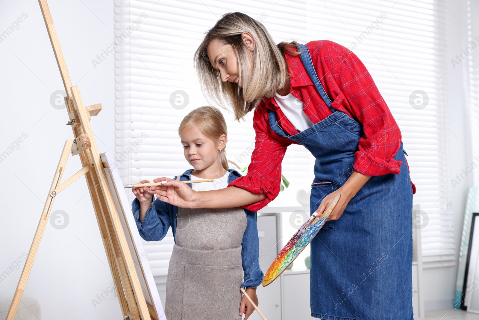 Photo of Choice of profession. Mother teaching her daughter to paint in studio