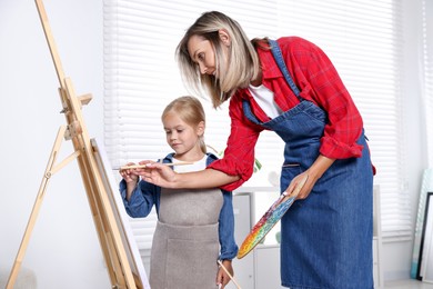 Photo of Choice of profession. Mother teaching her daughter to paint in studio