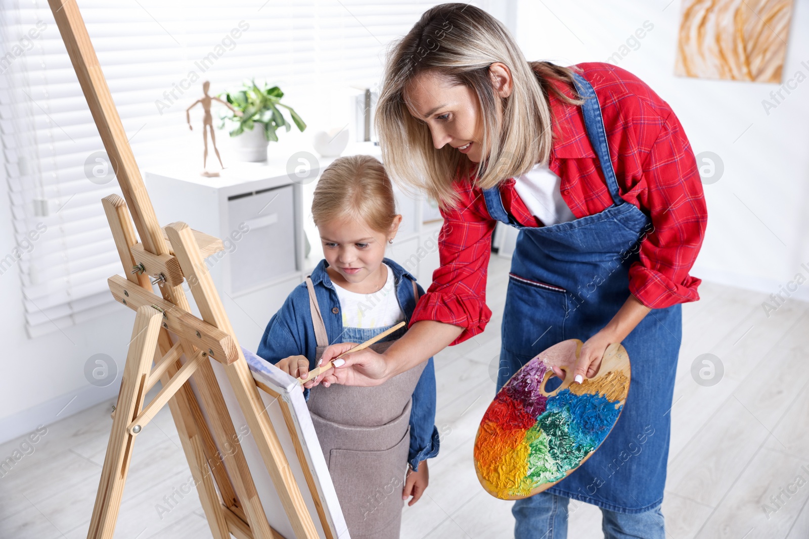 Photo of Choice of profession. Mother teaching her daughter to paint in studio