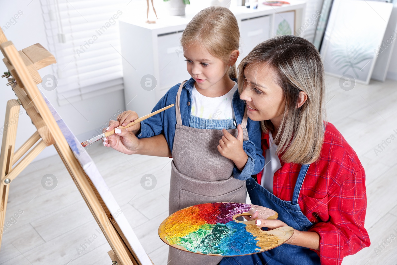 Photo of Choice of profession. Mother teaching her daughter to paint in studio