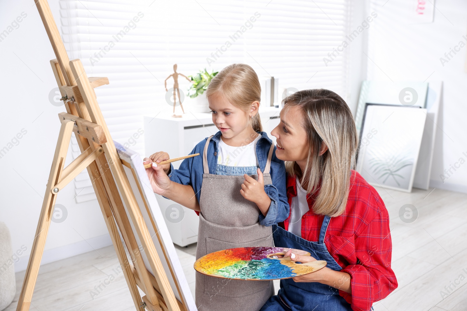 Photo of Choice of profession. Mother teaching her daughter to paint in studio