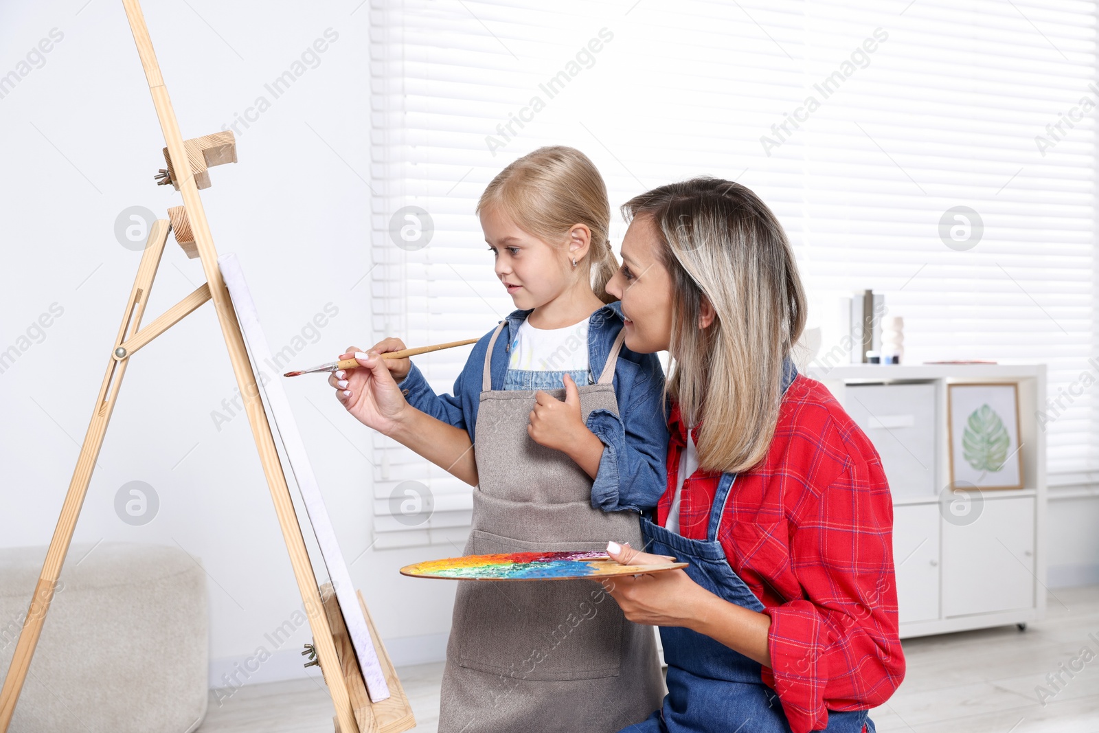 Photo of Choice of profession. Mother teaching her daughter to paint in studio