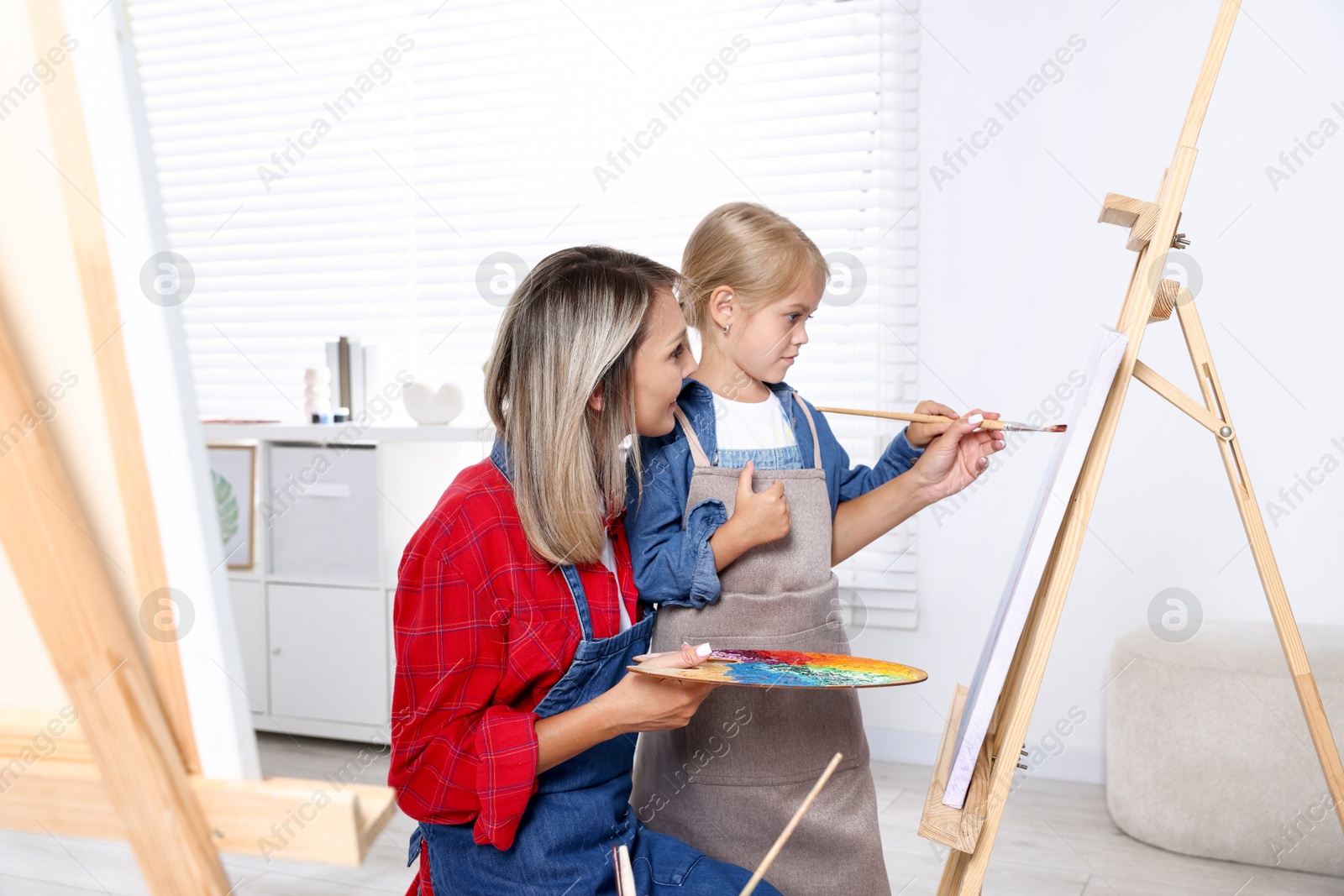Photo of Choice of profession. Mother teaching her daughter to paint in studio