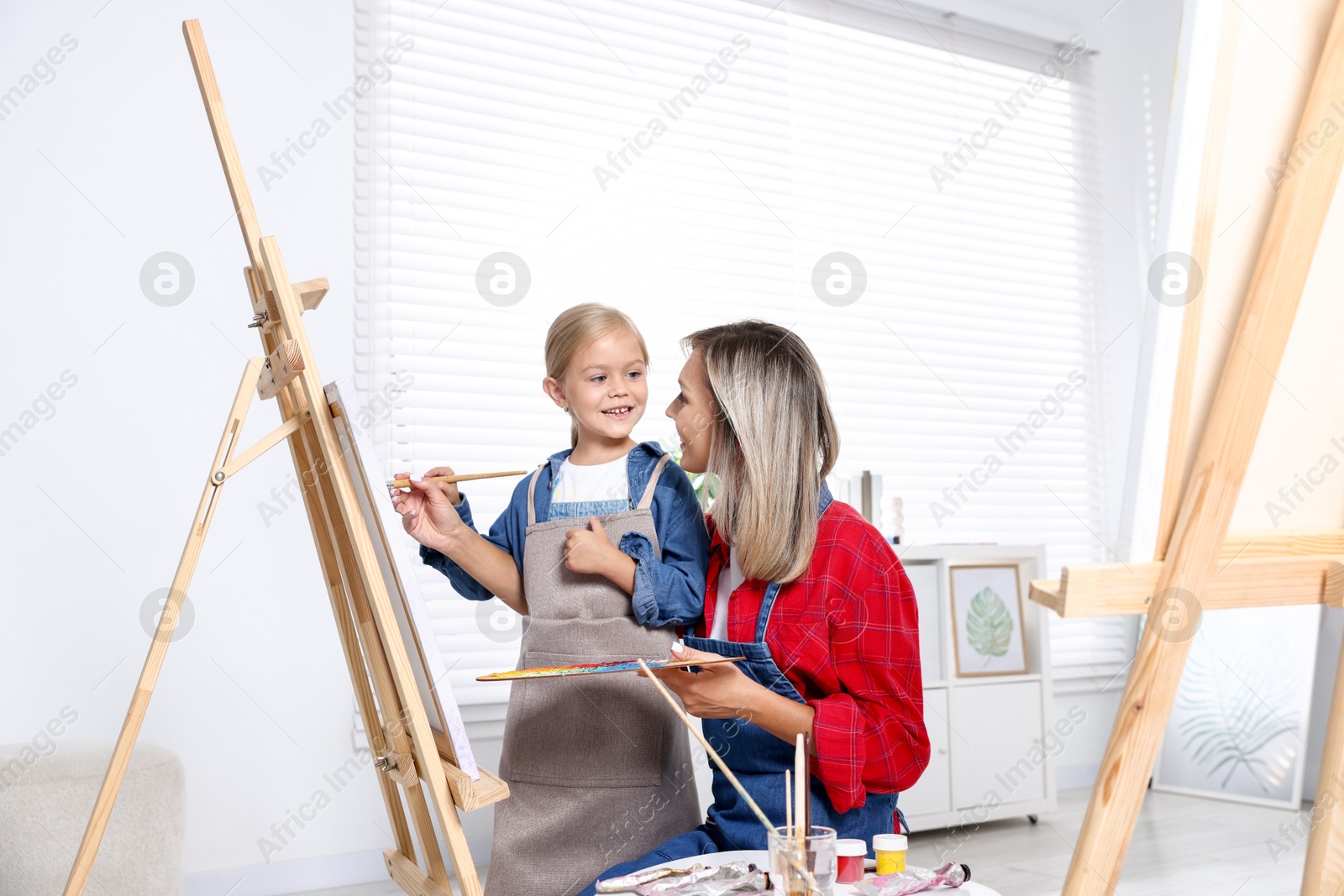 Photo of Choice of profession. Mother teaching her daughter to paint in studio