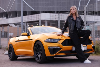 Photo of Stylish senior woman near modern cabriolet outdoors