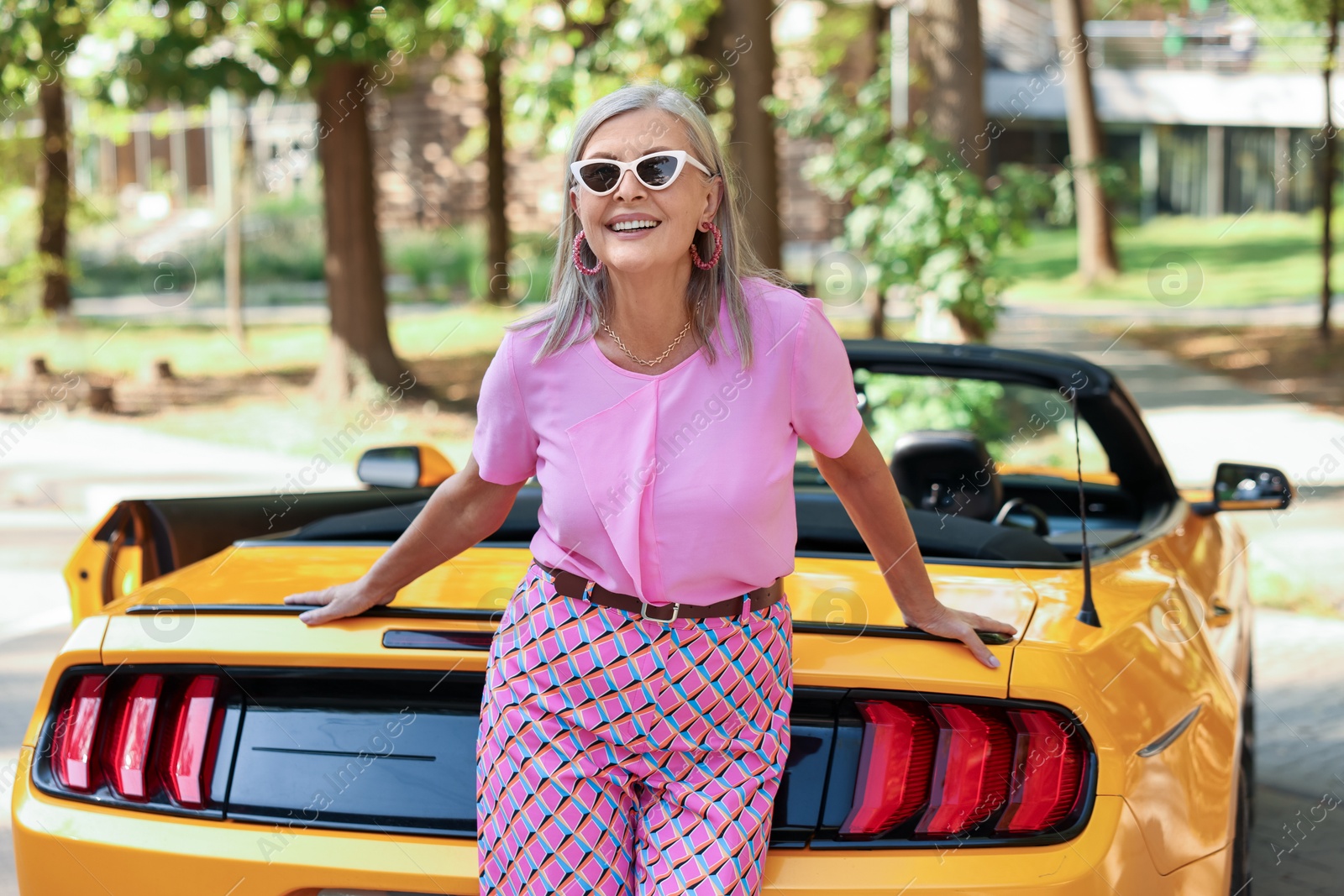 Photo of Stylish senior woman in sunglasses near modern cabriolet outdoors