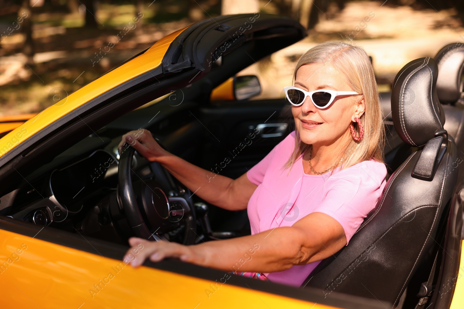 Photo of Stylish senior woman in sunglasses driving modern cabriolet outdoors