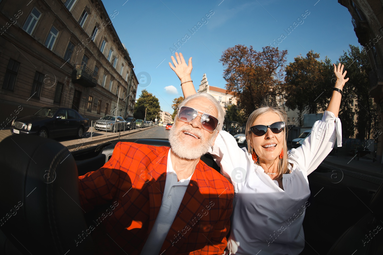 Senior couple enjoying cabriolet ride in city, wide angle lens Photo of Senior couple enjoying cabriolet ride in city, wide angle lens