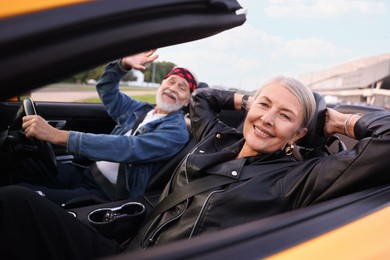 Photo of Stylish senior couple enjoying cabriolet ride outdoors, selective focus