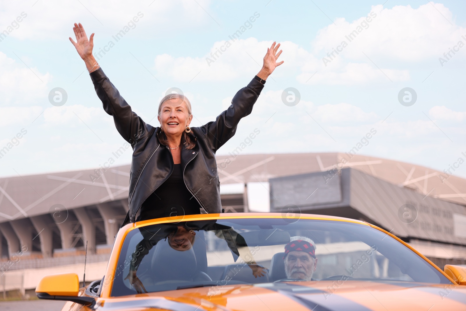 Senior couple enjoying cabriolet ride in city. Woman with wide open arms Photo of Senior couple enjoying cabriolet ride in city. Woman with wide open arms