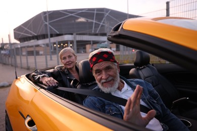 Photo of Senior couple in modern cabriolet outdoors, selective focus