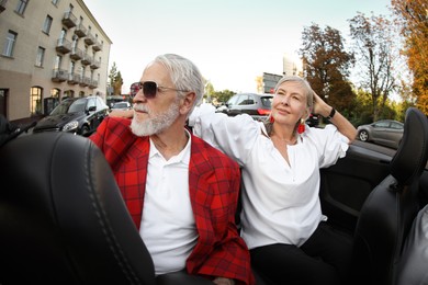 Photo of Senior couple enjoying cabriolet ride in city, wide angle lens