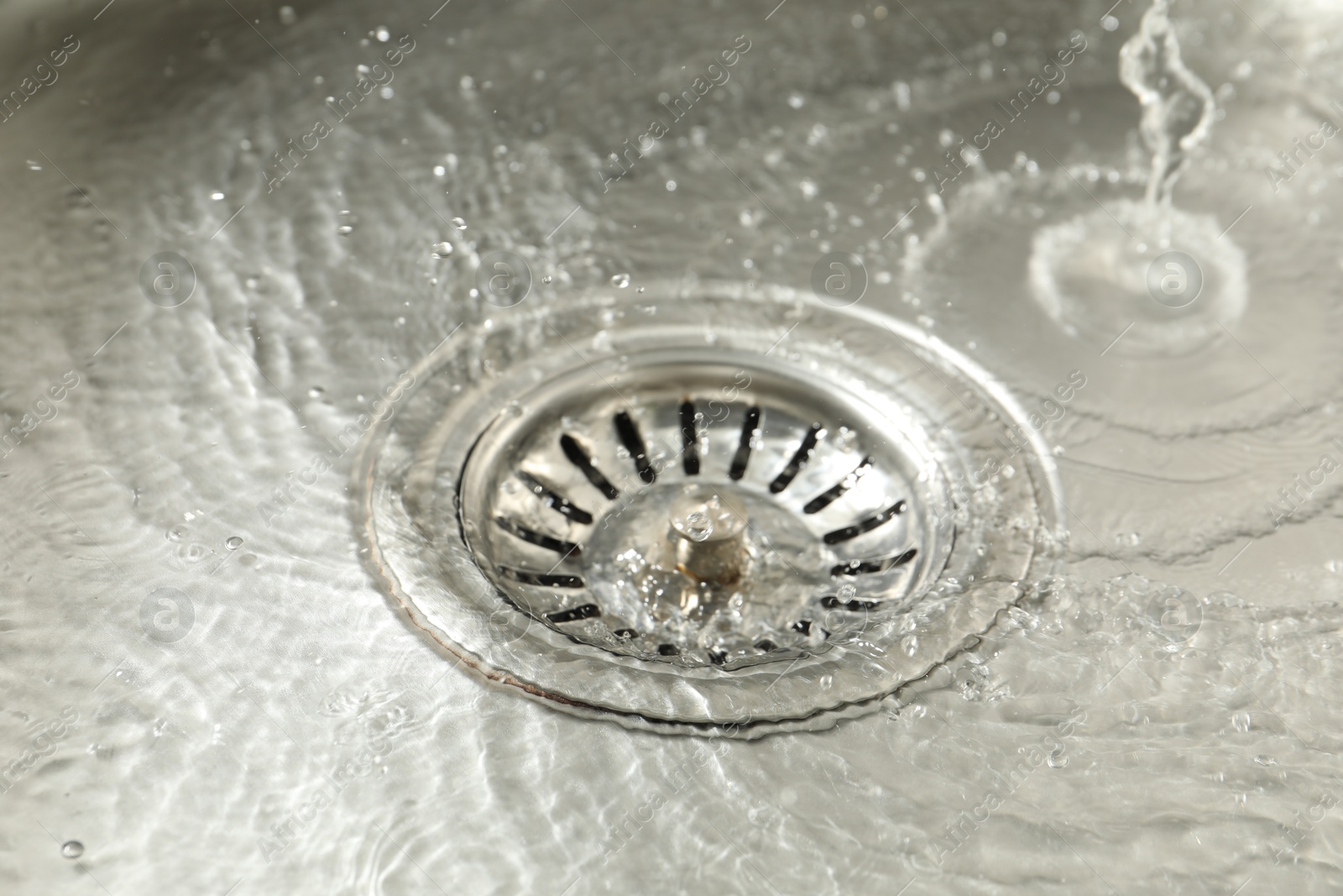 Photo of Water going down sink drain, closeup view