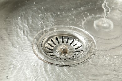 Photo of Water going down sink drain, closeup view