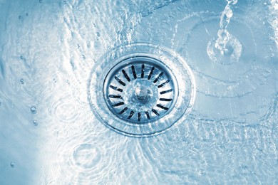 Photo of Water going down sink drain, closeup view