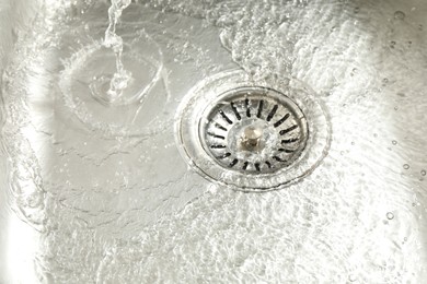 Photo of Water going down sink drain, closeup view