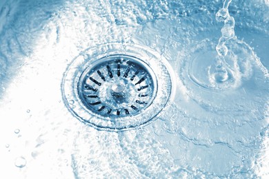 Photo of Water going down sink drain, closeup view