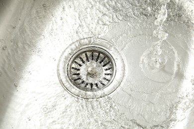 Photo of Water going down sink drain, closeup view