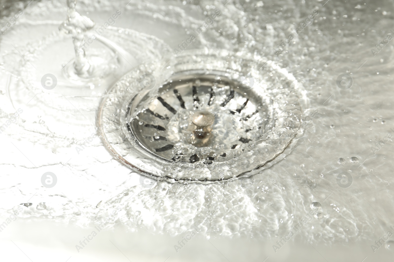 Photo of Water going down sink drain, closeup view