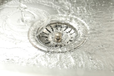 Photo of Water going down sink drain, closeup view