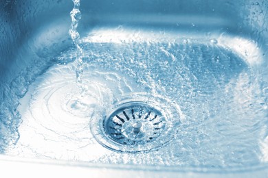 Photo of Water going down sink drain, closeup view
