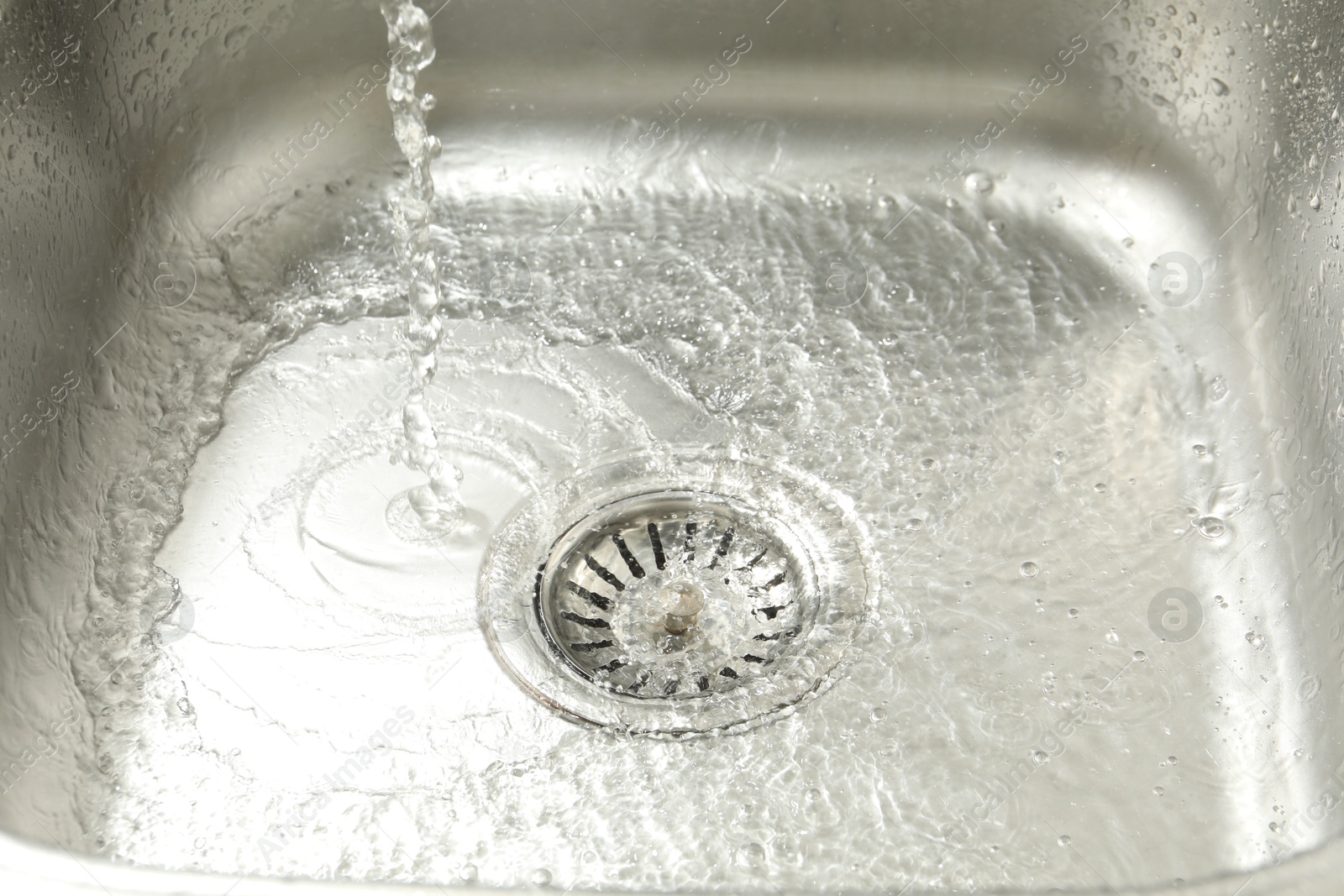 Photo of Water going down sink drain, closeup view