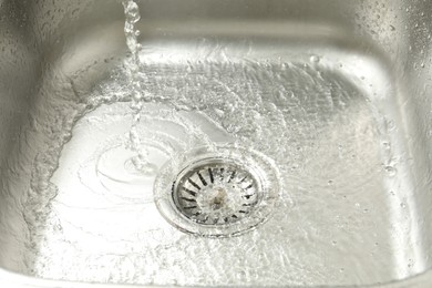 Photo of Water going down sink drain, closeup view