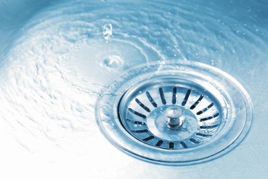 Photo of Water going down sink drain, closeup view