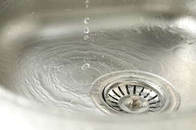 Photo of Water going down sink drain, closeup view