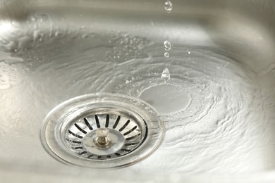 Photo of Water going down sink drain, closeup view