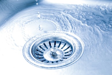 Photo of Water going down sink drain, closeup view