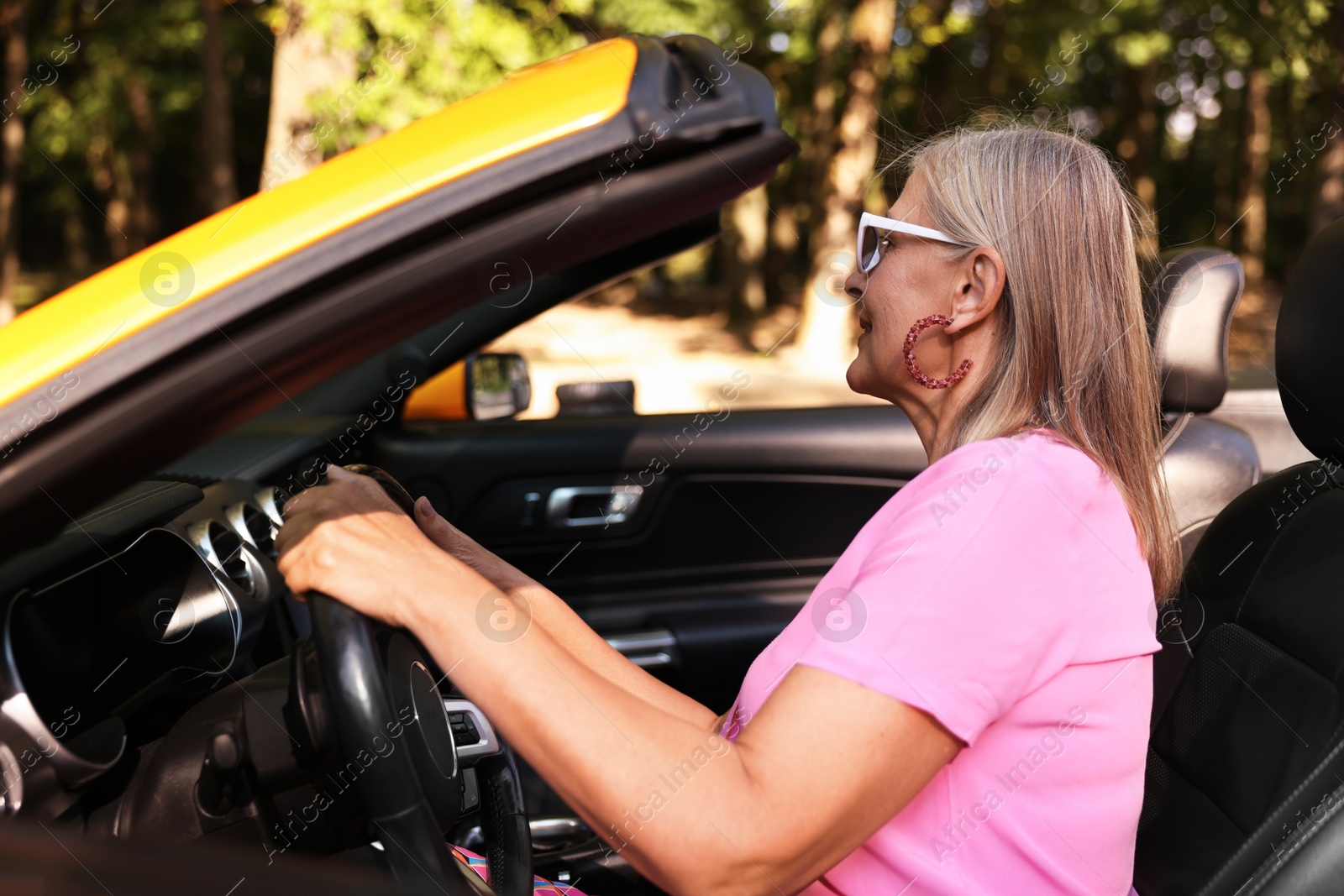 Photo of Stylish senior woman in sunglasses driving modern cabriolet outdoors