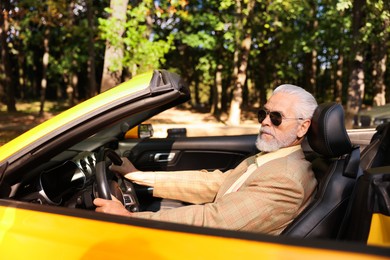 Photo of Stylish senior man in sunglasses driving modern cabriolet outdoors