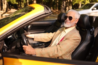 Photo of Stylish senior man in sunglasses driving modern cabriolet outdoors