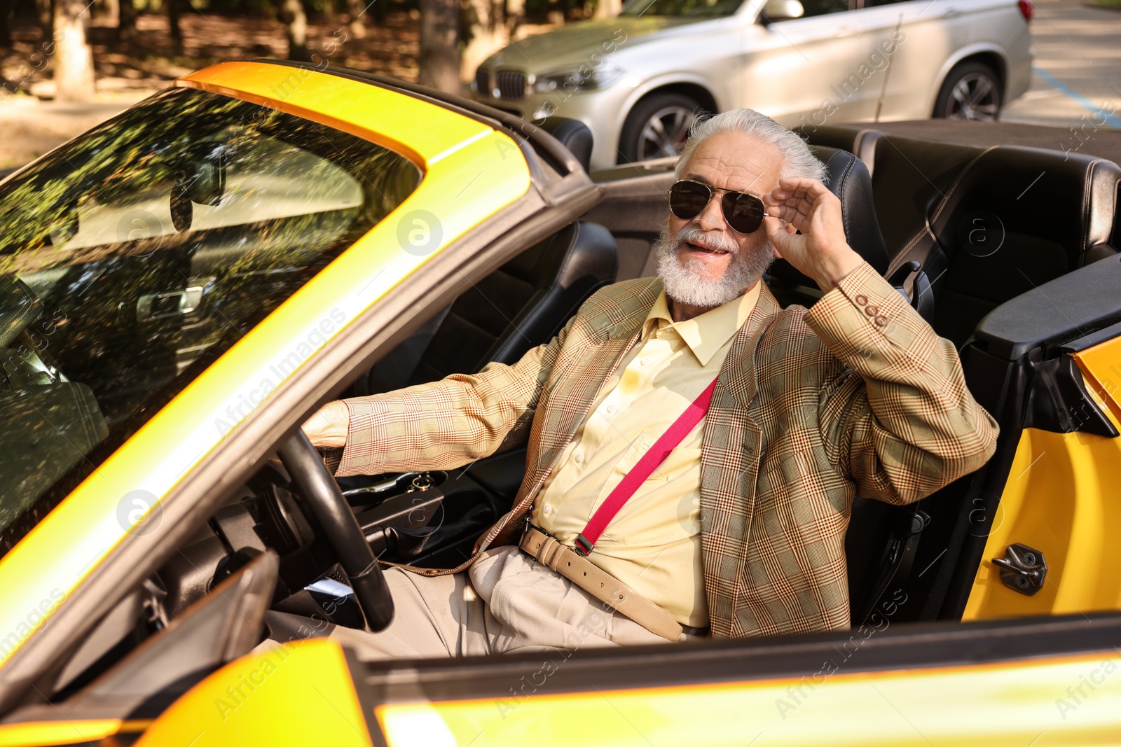 Stylish senior man in sunglasses driving modern cabriolet outdoors Photo of Stylish senior man in sunglasses driving modern cabriolet outdoors