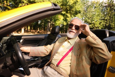 Photo of Stylish senior man in sunglasses driving modern cabriolet outdoors