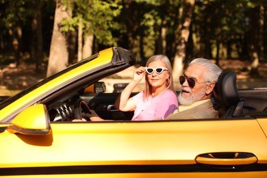 Photo of Senior couple enjoying cabriolet ride in city, selective focus