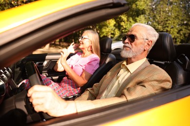 Photo of Senior couple enjoying cabriolet ride in city, selective focus