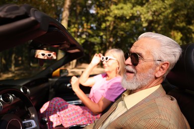 Photo of Senior couple enjoying cabriolet ride in city, selective focus
