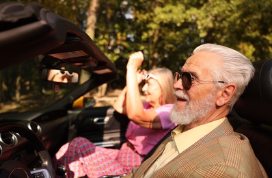 Photo of Senior couple enjoying cabriolet ride in city, selective focus